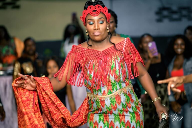 La mariée danse en tenue rouge et coiffe traditionnelle pendant le coutumier