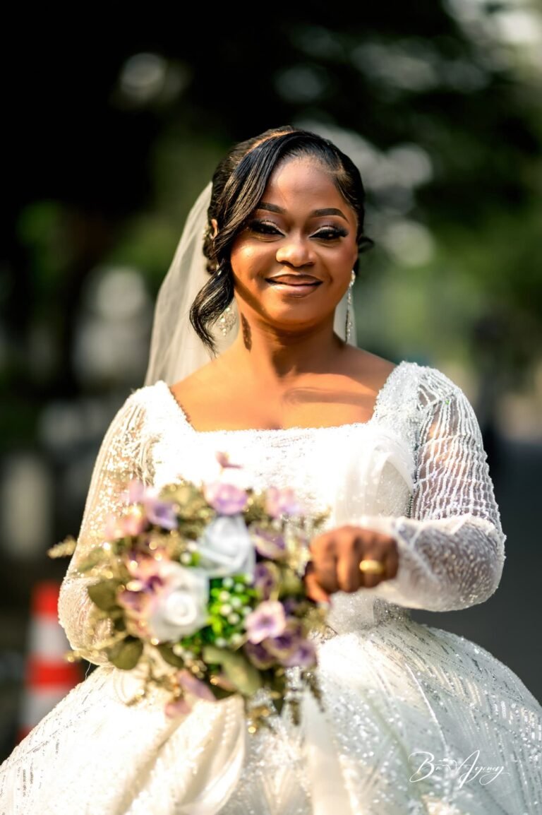 La mariée sourit avec son bouquet sous les arbres