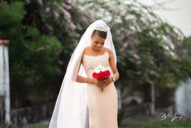 La mariée voilée tient un bouquet de roses rouges