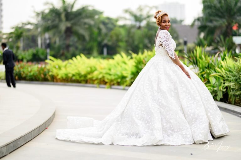 Une mariée en robe à longue traîne dans un jardin à Kinshasa