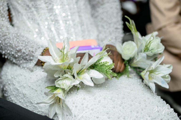 Détail de la robe de la mariée et de son bouquet de lys
