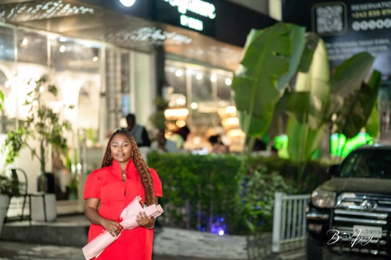 Jeune femme en robe rouge devant un restaurant le soir