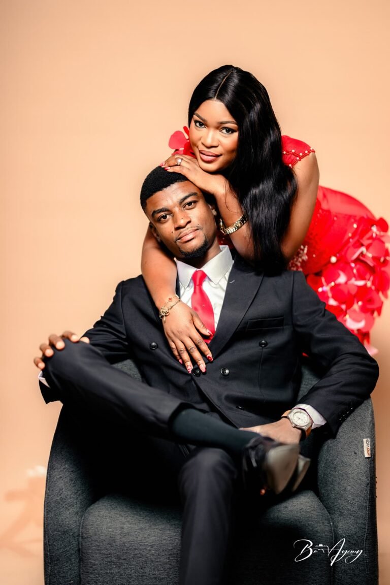 Couple en studio, l'homme assis dans un fauteuil, la femme en robe rouge